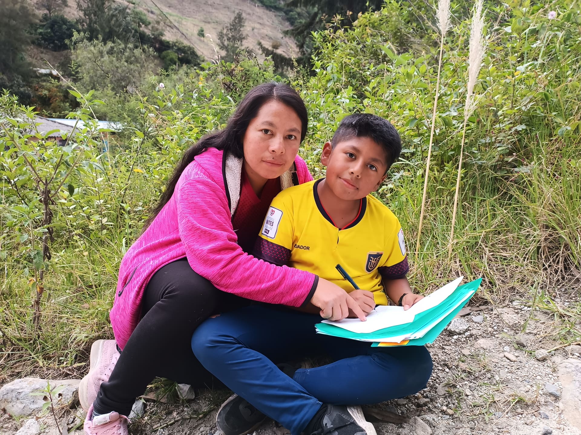 Madre acompañando a su hijo con las tareas escolares al aire libre