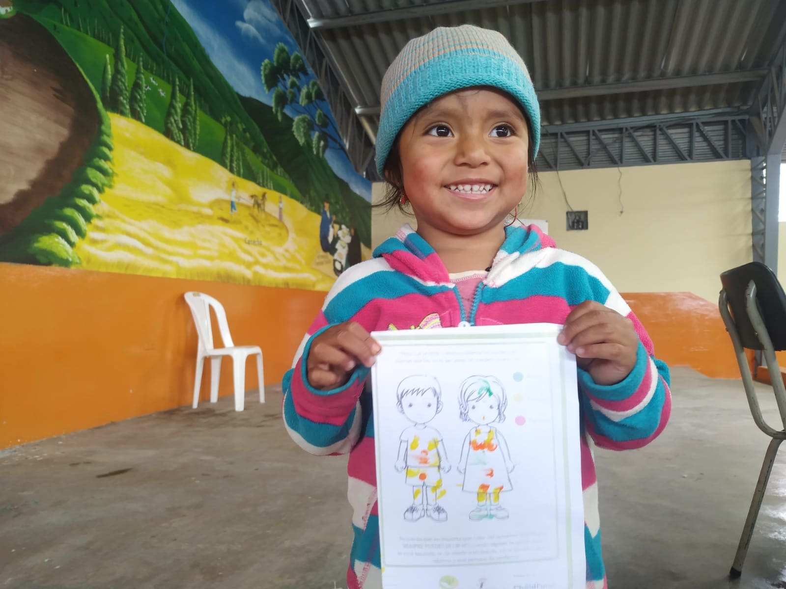 Niña sonriente mostrando su actividad educativa en un centro comunitario